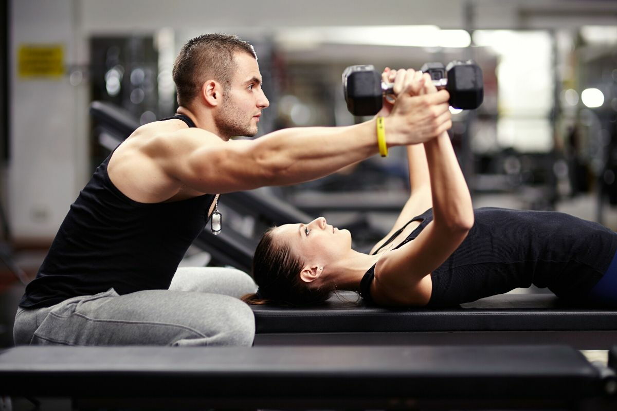 A girl trains with the personal trainer in the gym