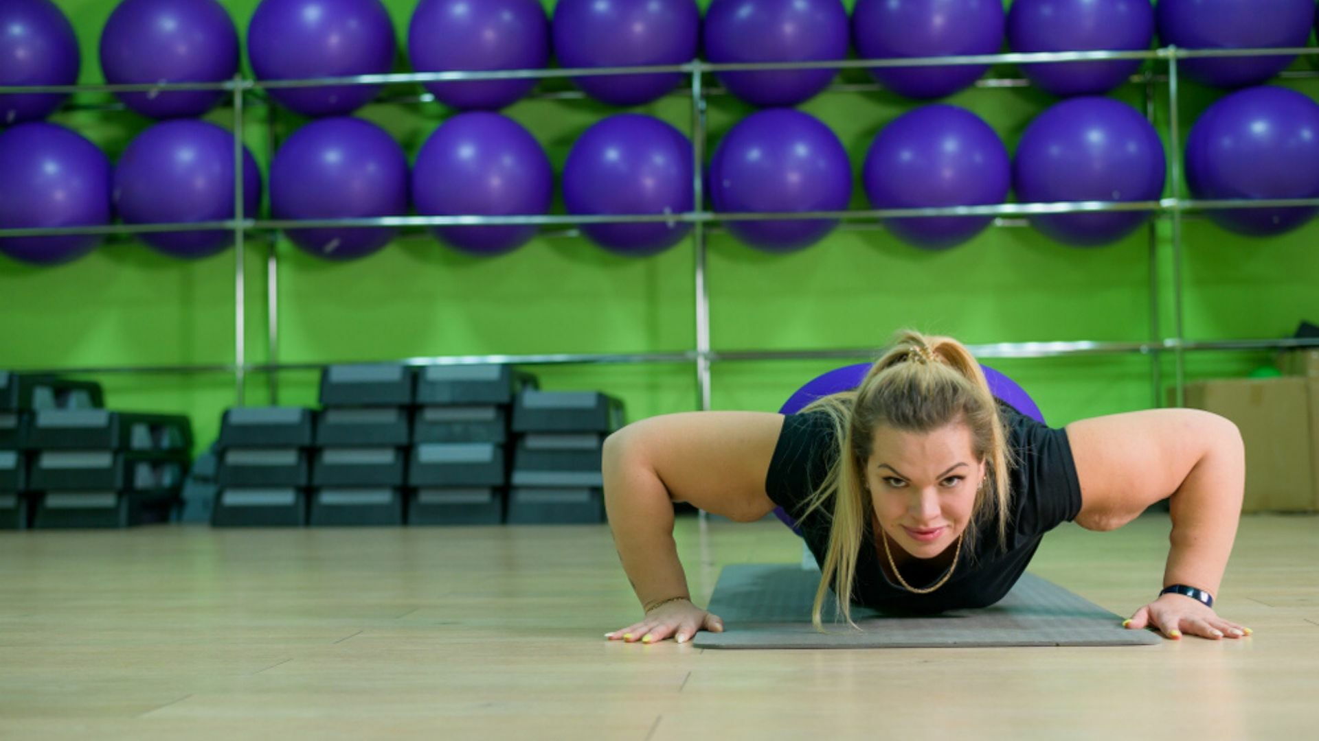 mujer con sobrepeso hace flexiones en el gimnasio