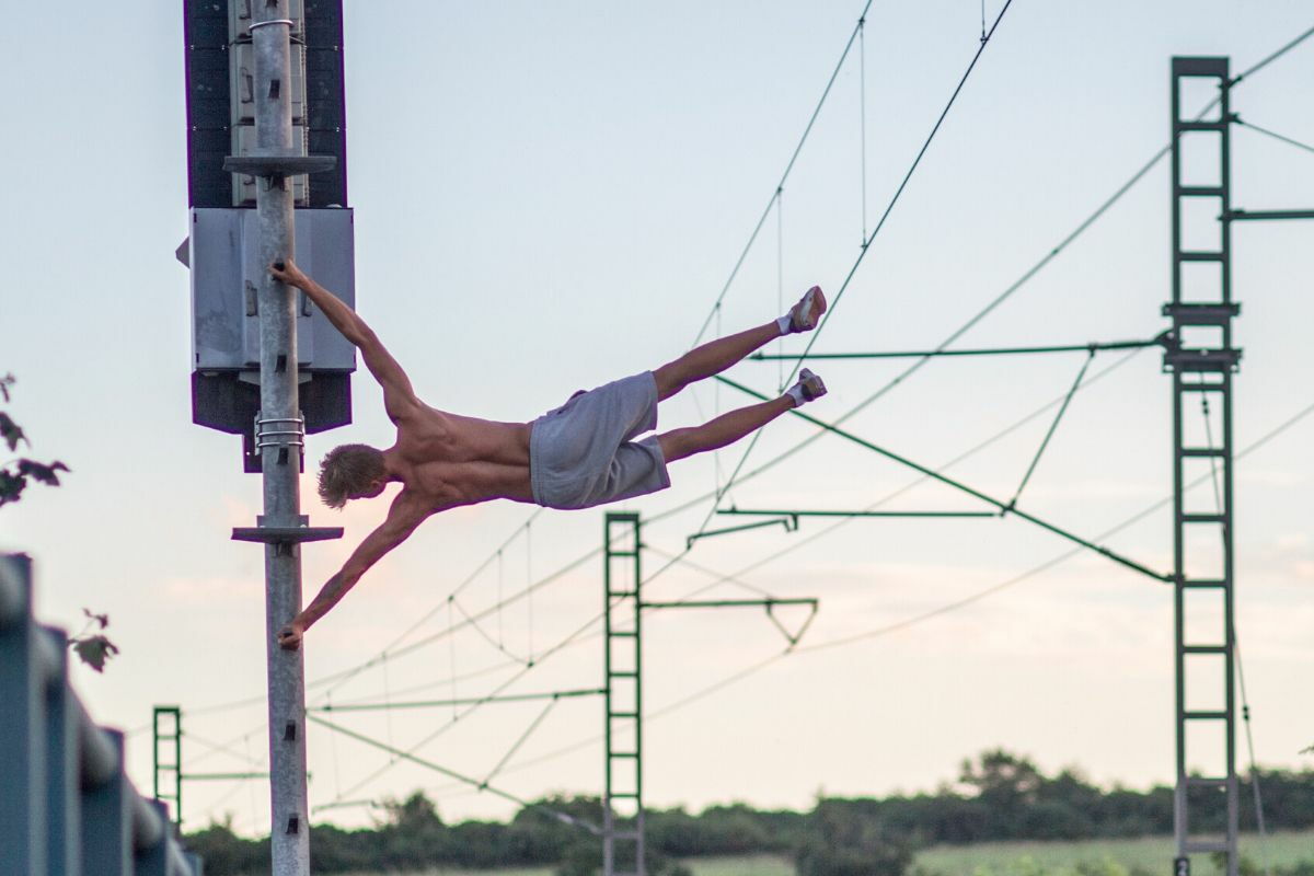 ragazzo che fa l'esercizio calistenico human flag (bandiera)