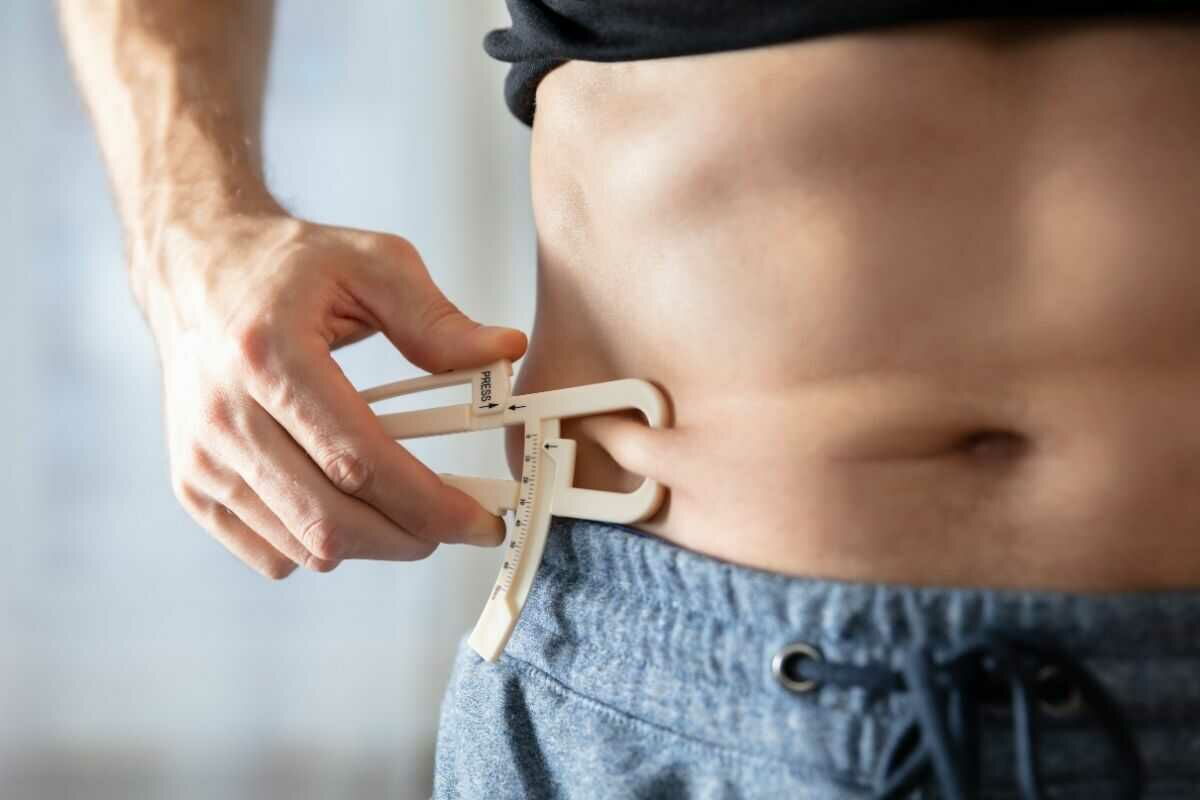 Man measures the fat mass on his abdomen