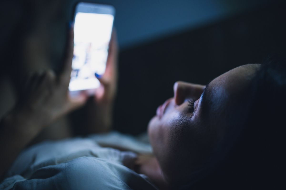 Mädchen, das nachts im Bett auf das Handy schaut