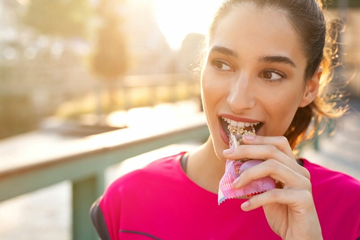 ragazza fa uno snack con una barretta proteica