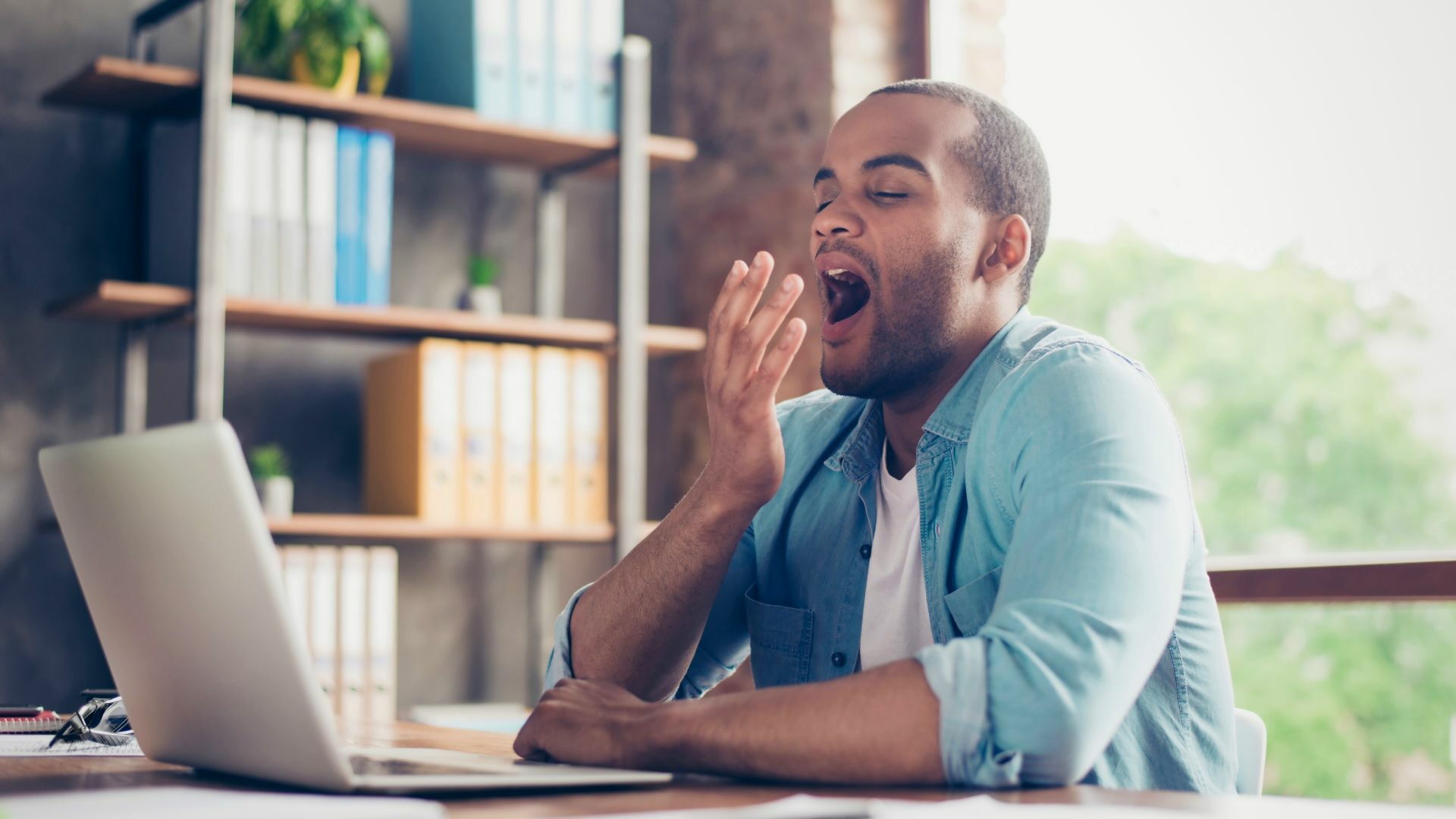 Man yawns and is sleepy at work